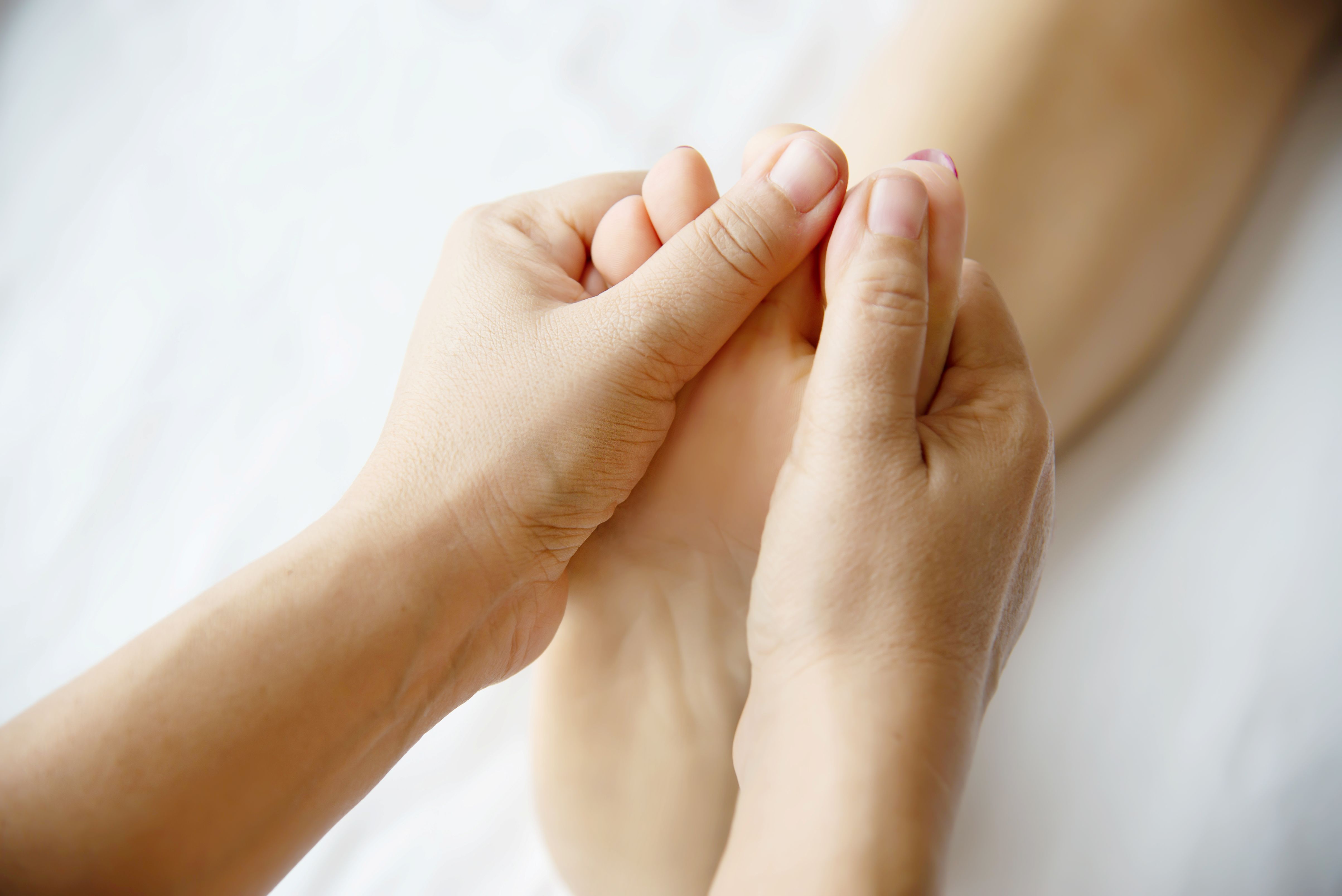 blanke vrouw die met ogen dicht op massagetafel ligt. ontvangt massage met twee handen op schouders 